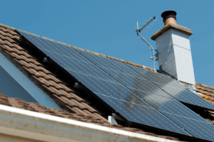 Photo of a roof with solar panels under a blue sky.