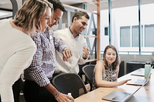 A photo of four people looking at a laptop.