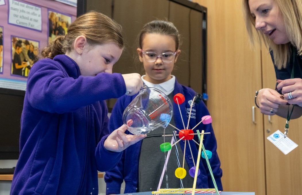 Two school children pour water on a model to show renewable energy