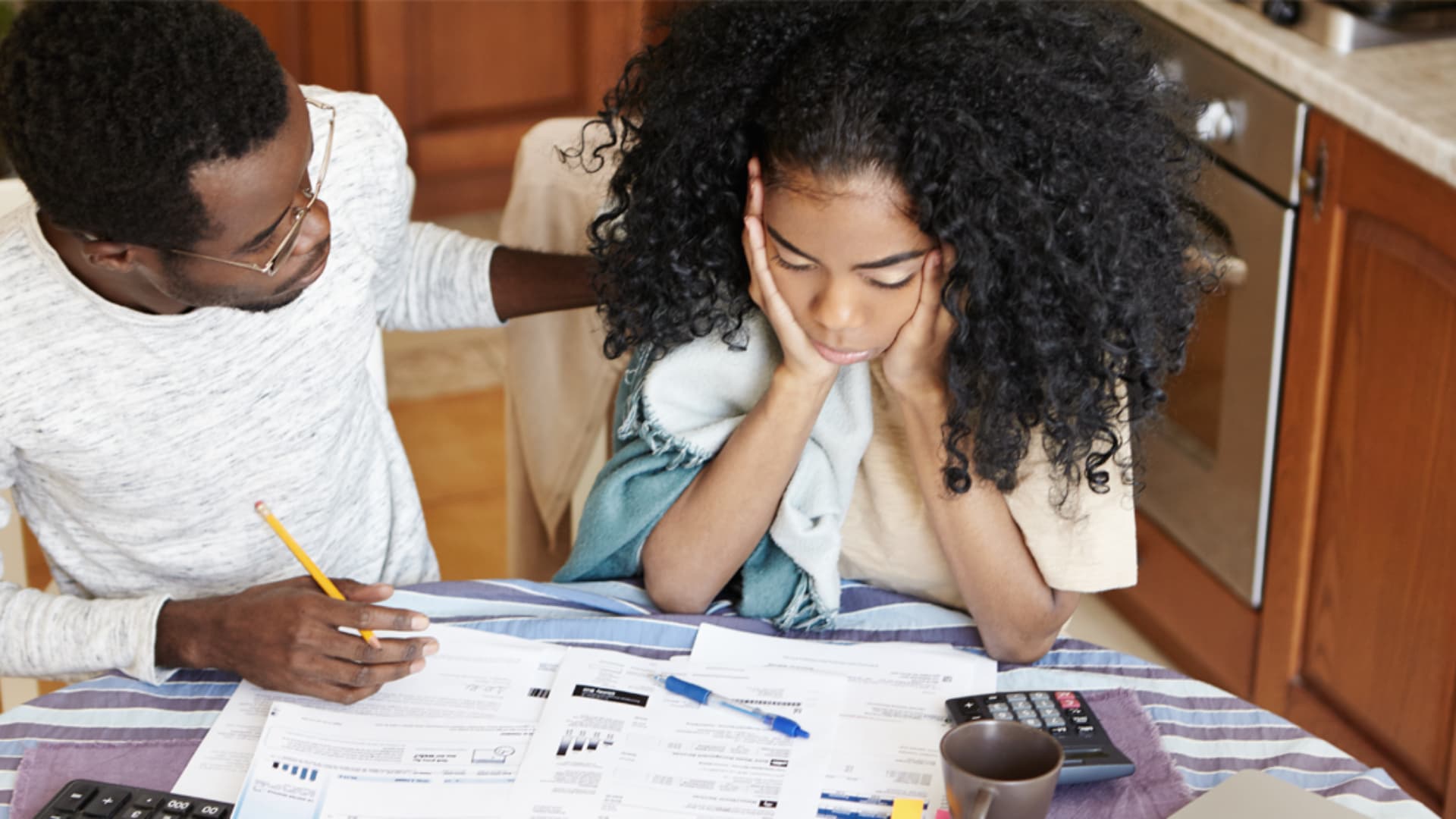 A photo of a couple looking at their household bills and looking concerned.