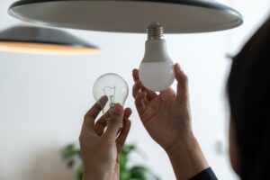 Photograph of someone exchanging an old lightbulb for an energy efficient one.
