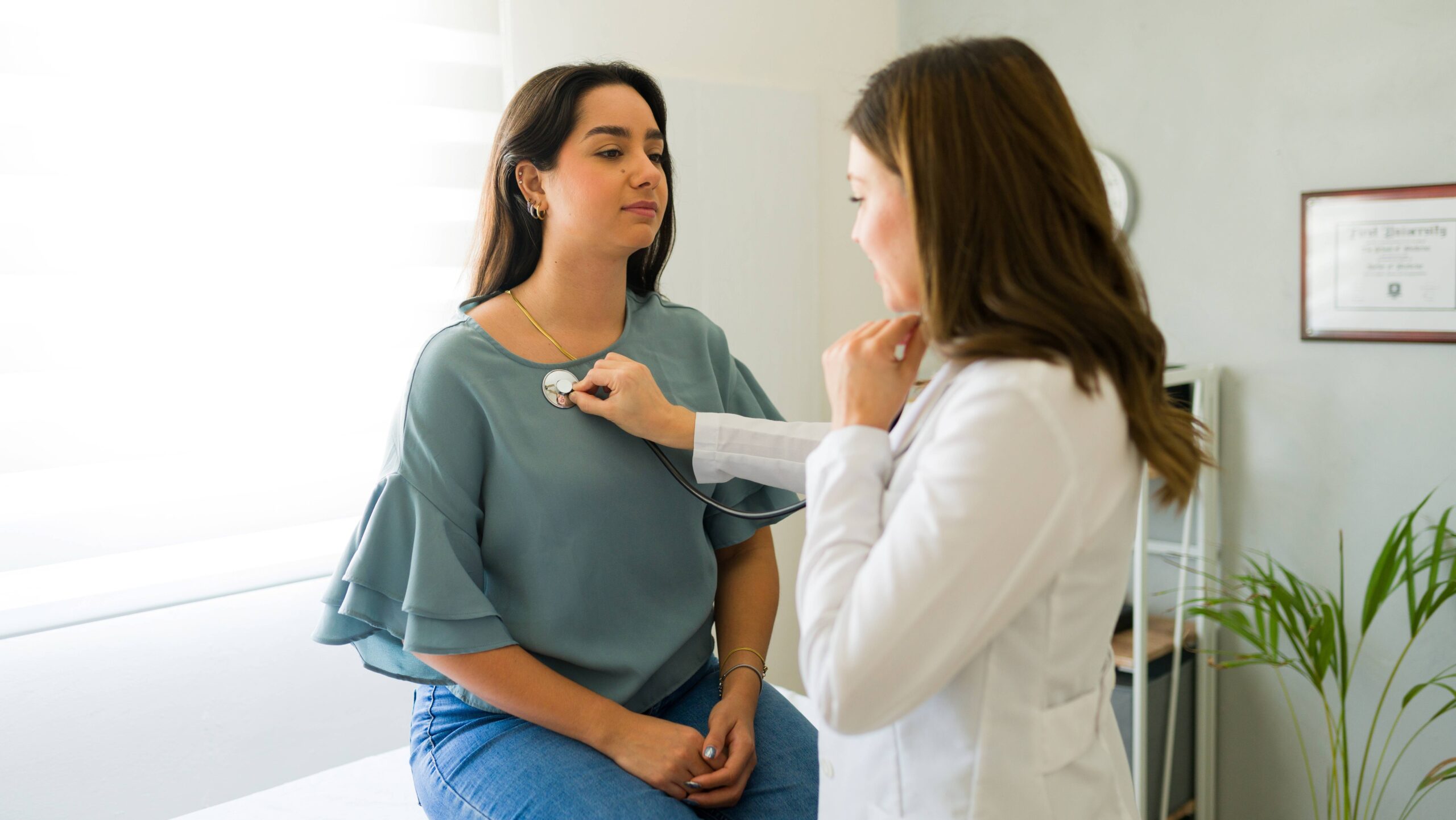 Stock photo of a woman receiving a medical check up from a doctor. The doctor is using a stethoscope.