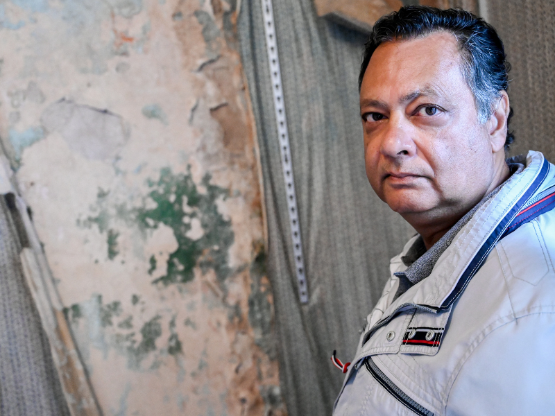 A photo of a client that National Energy Action helped in Fishwick. He is stood in front of a wall covered in green mould caused by poor insulation.
