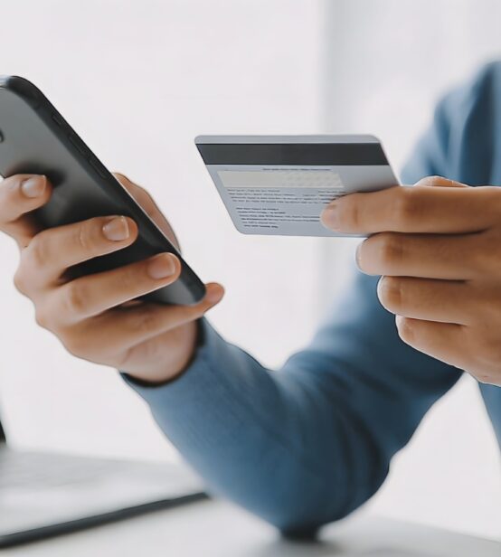 Stock photo of someone holding a smartphone and their credit or debit card.