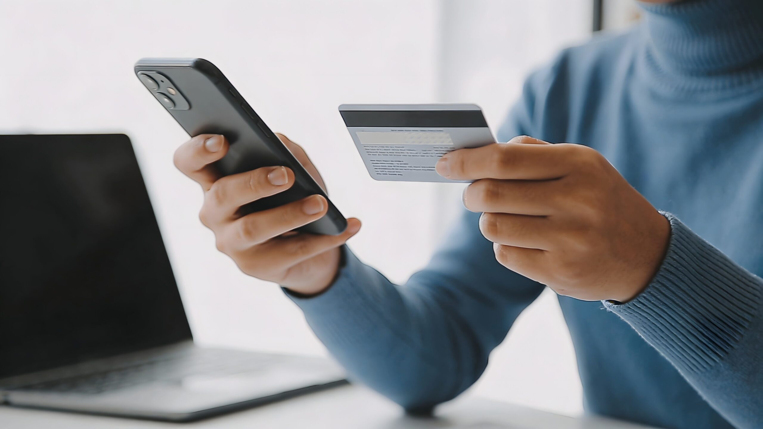 Stock photo of someone holding a smartphone and their credit or debit card.
