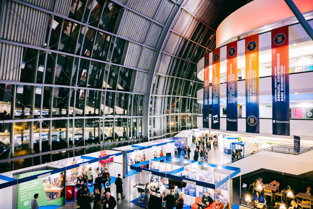 A photo of National Energy Action's annual conference taken at the Glasshouse in Gateshead. Inside the large domed building, you can see an exhibition with our members talking to delegates about how they can help fight fuel poverty.