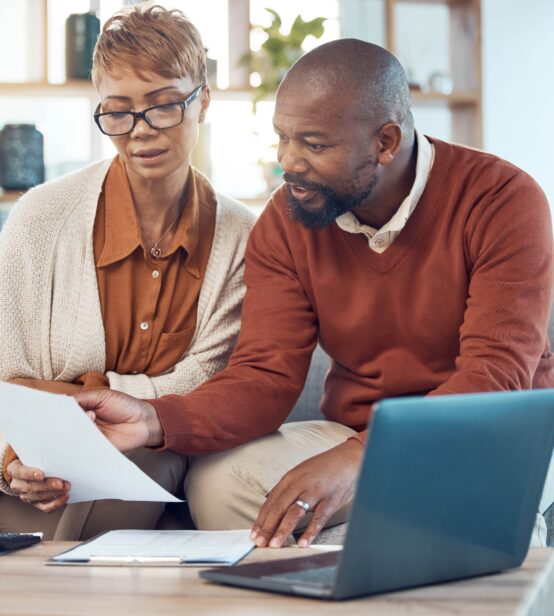 Stock photo of a middle-aged couple sitting on their sofa looking over their finances.