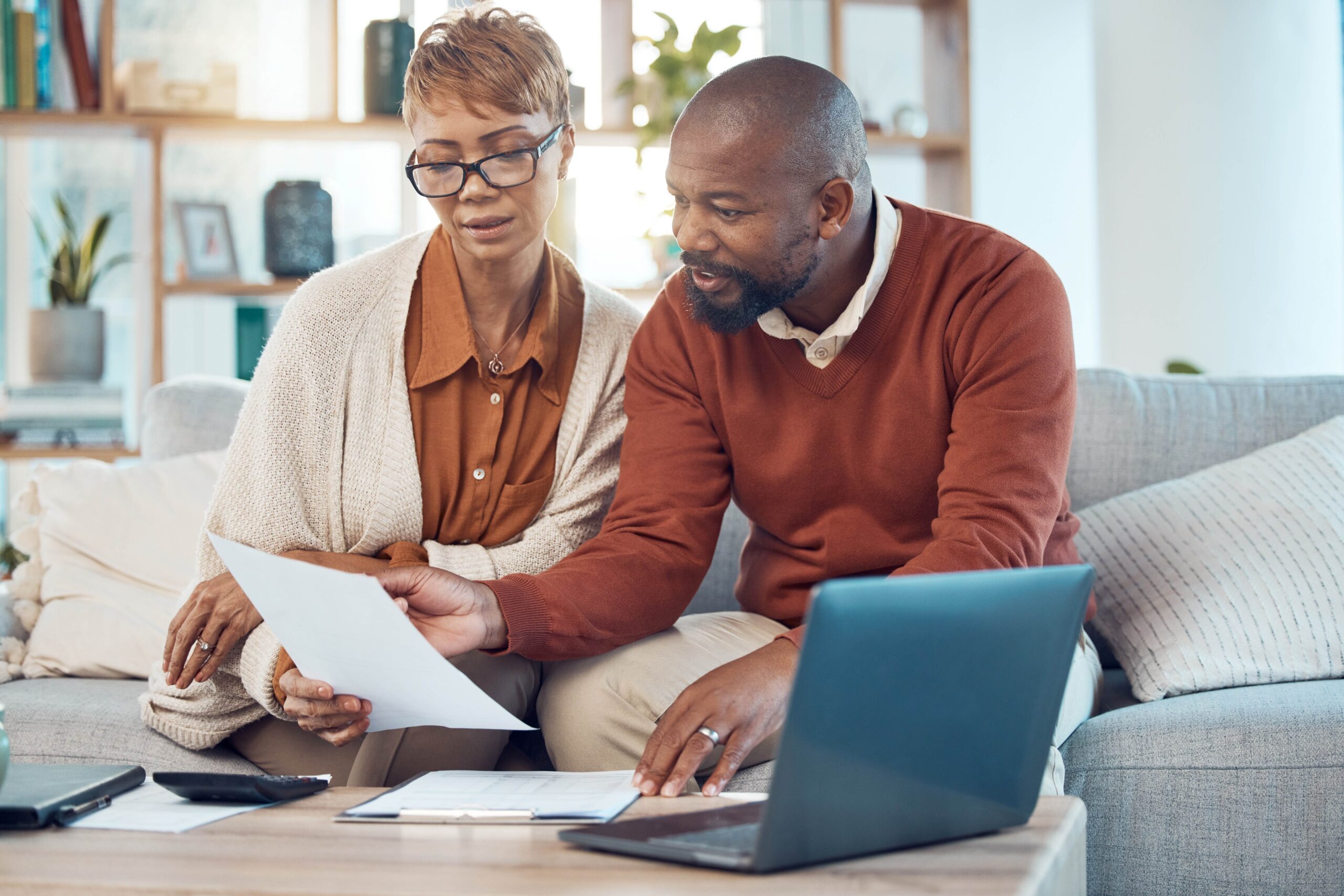 Stock photo of a middle-aged couple sitting on their sofa looking over their finances.