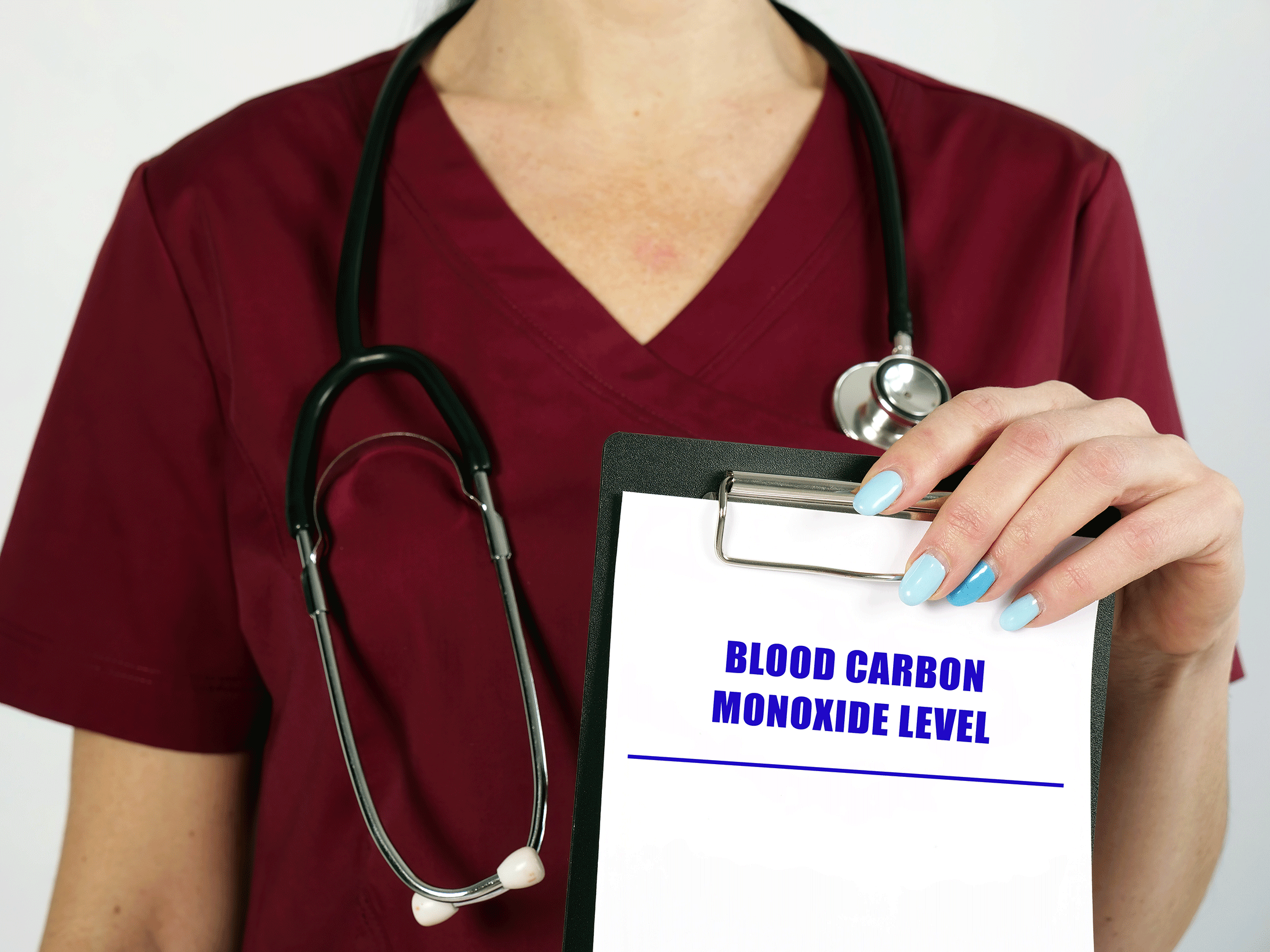 Stock photo of a female medical professional with a stethoscope holding a clipboard that says 'Blood carbon monoxide level' on it.