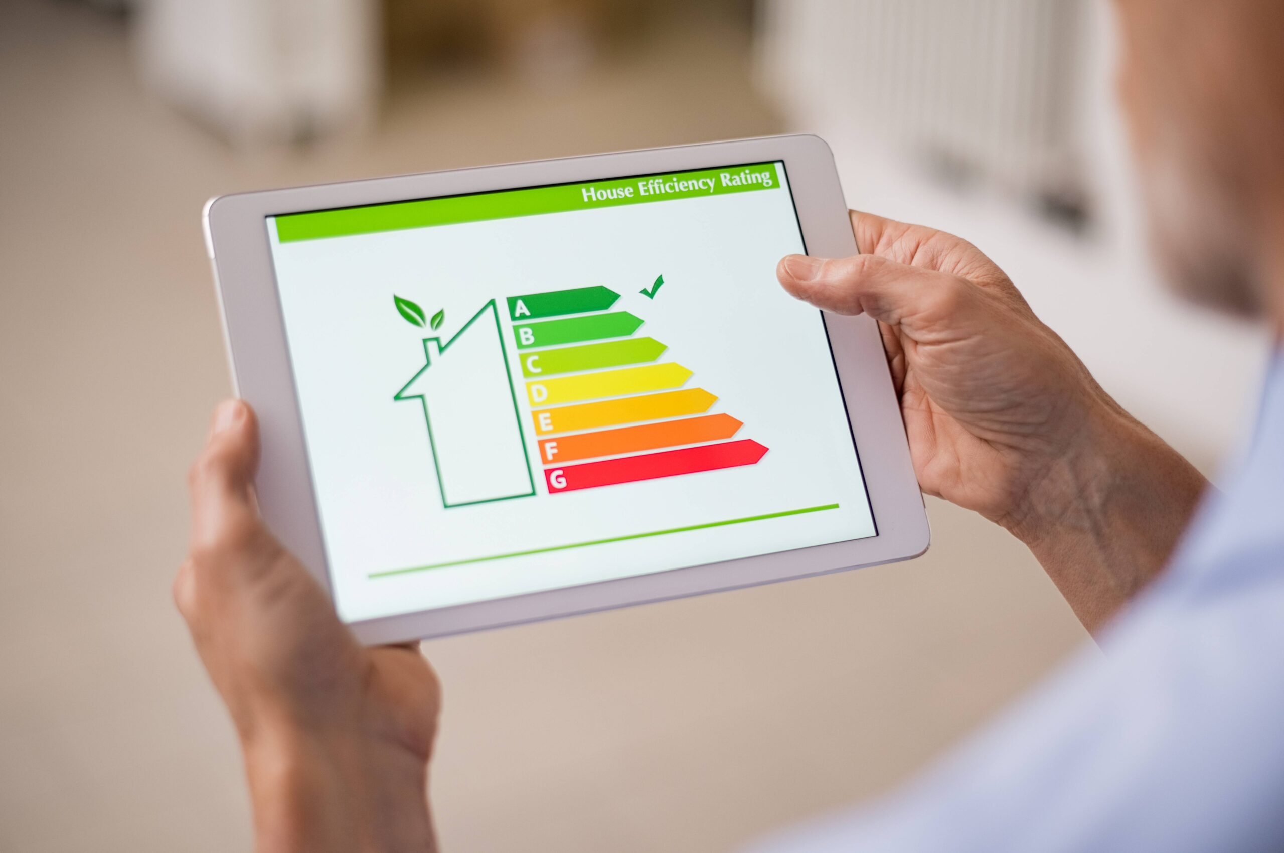 Stock photo showing someone holding a tablet showing a home's energy efficiency rating. There is a tick next to 'A' on the scale.