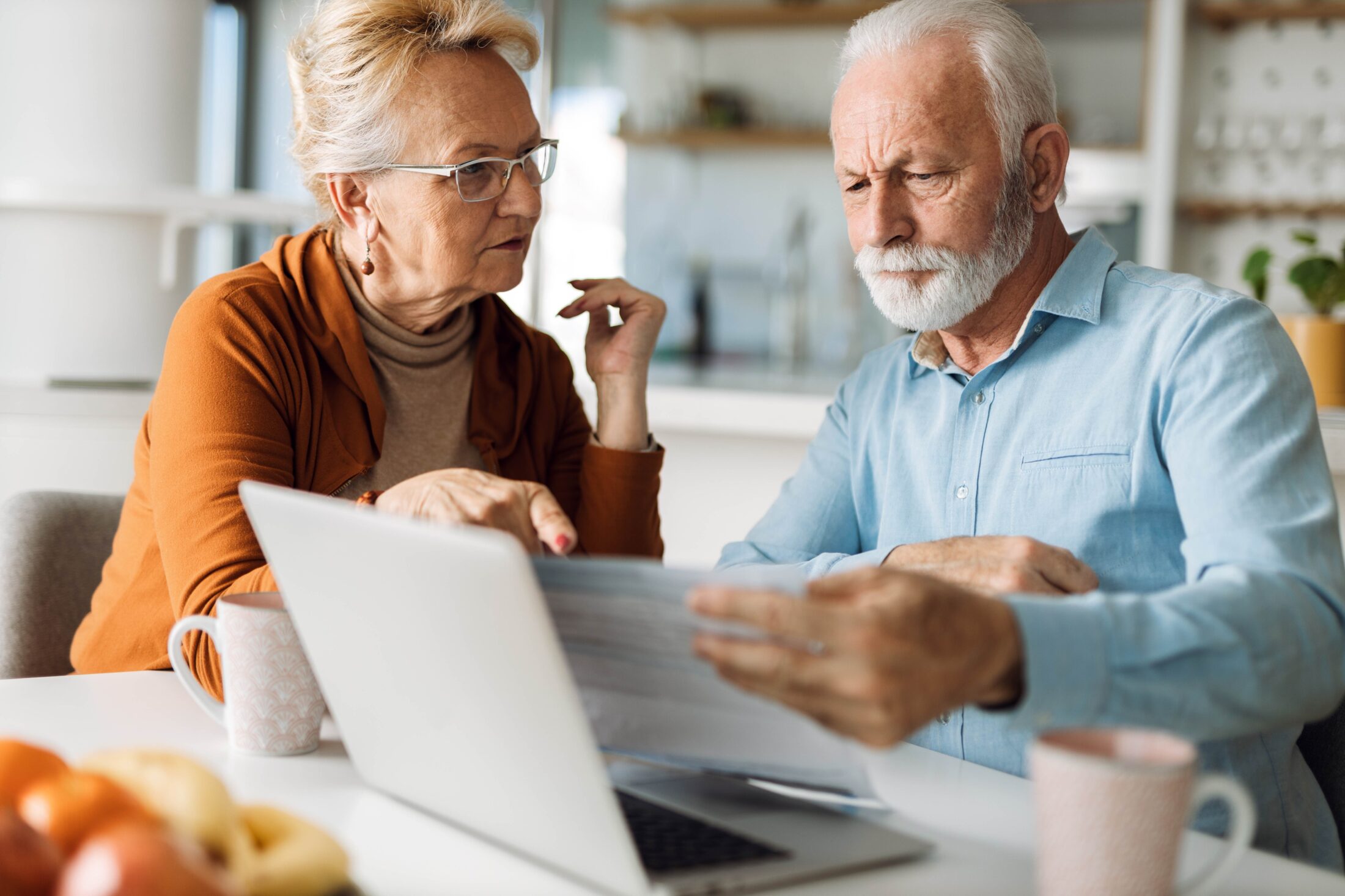 A photo of an older couple looking at a laptop.