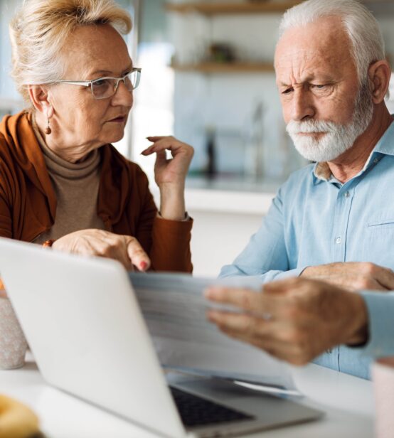 A photo of an older couple looking at a laptop.