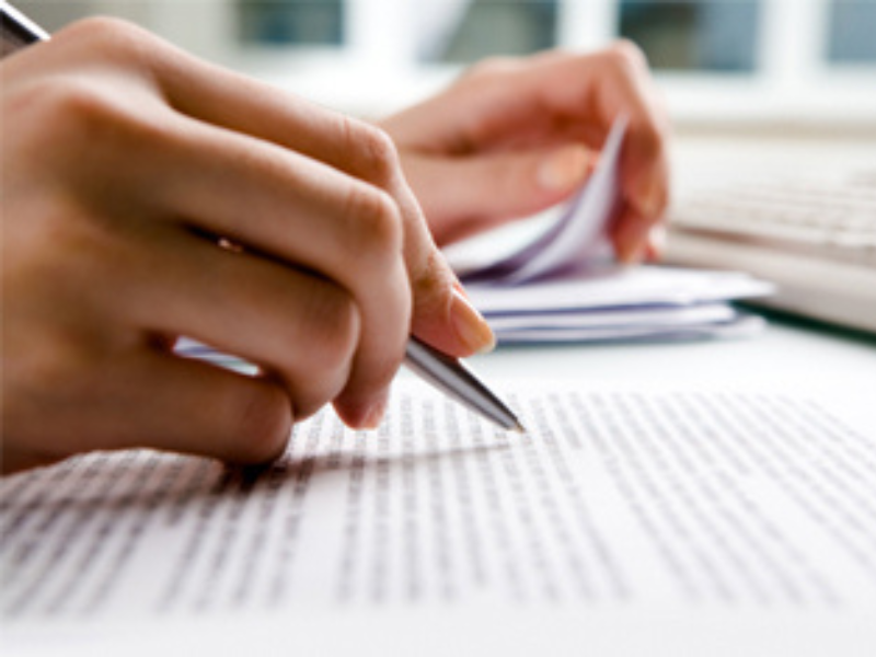 Close-up hands writing on lined paper with pen on a desk